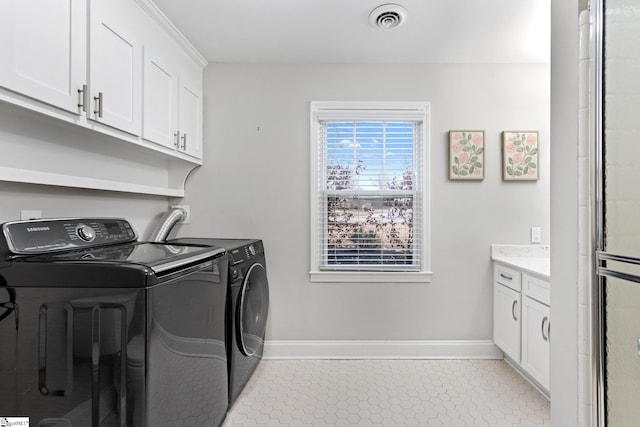 laundry area featuring separate washer and dryer, cabinets, and light tile patterned floors