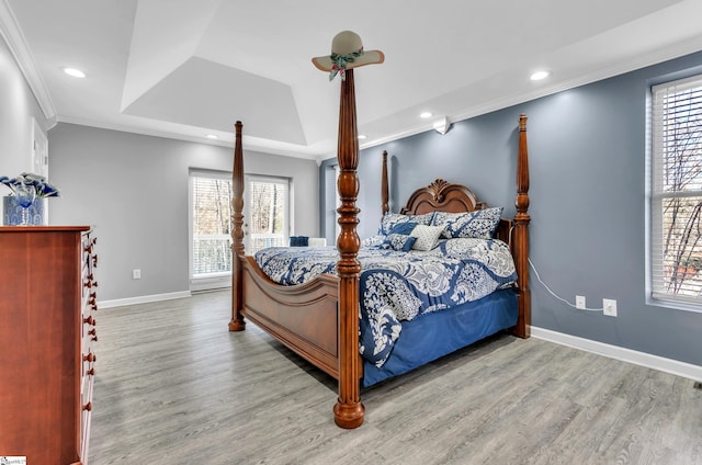 bedroom featuring crown molding, light hardwood / wood-style floors, and a tray ceiling