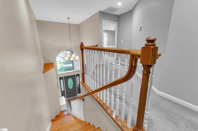 stairway featuring a high ceiling, hardwood / wood-style floors, and a notable chandelier