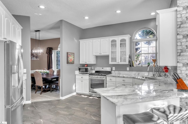 kitchen with pendant lighting, kitchen peninsula, white cabinets, and stainless steel appliances