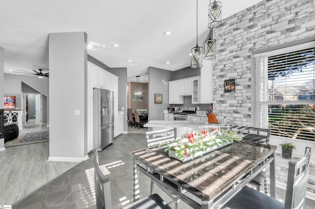 kitchen with ceiling fan, appliances with stainless steel finishes, decorative light fixtures, white cabinets, and light stone counters