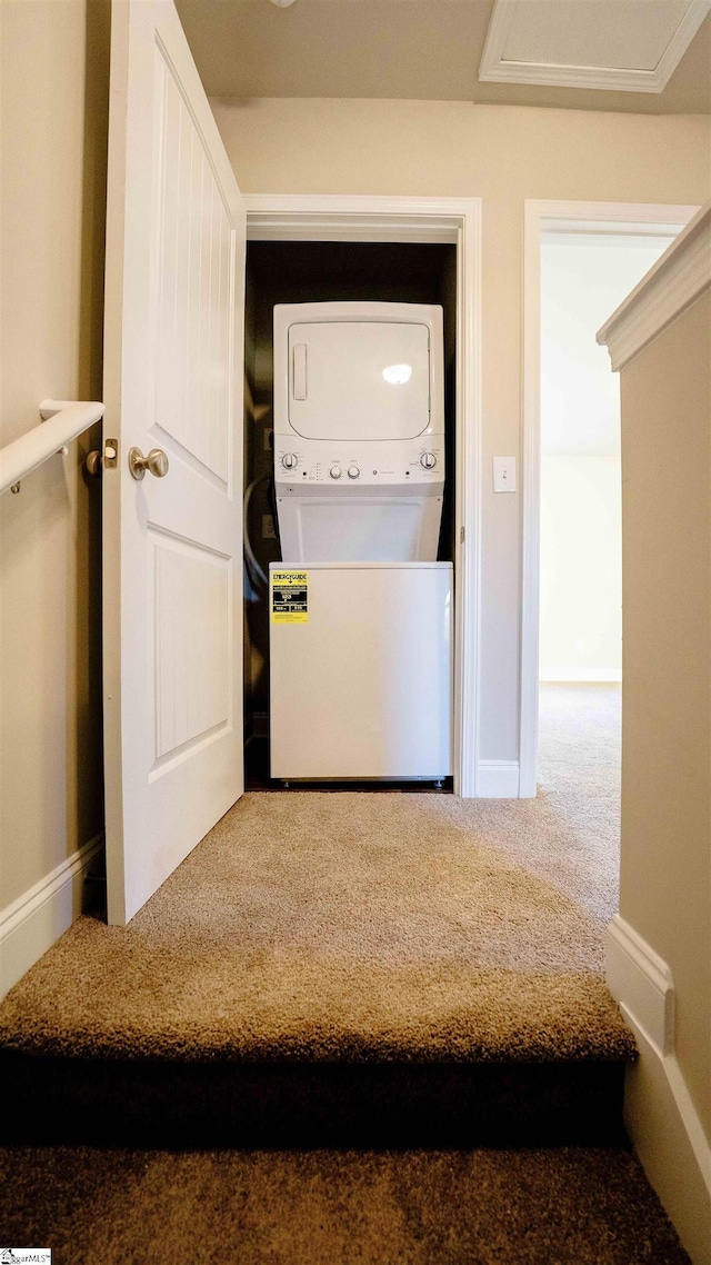 clothes washing area featuring carpet floors and stacked washer and dryer