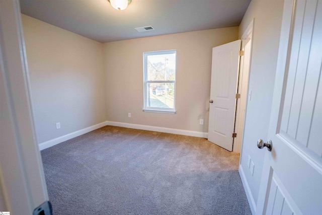 spare room featuring dark colored carpet