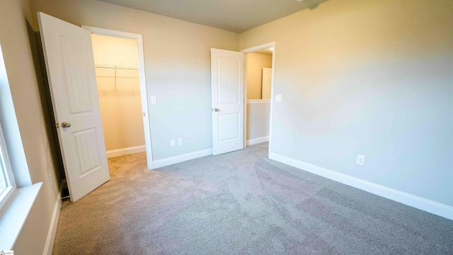 unfurnished bedroom with a walk in closet, light colored carpet, and a closet