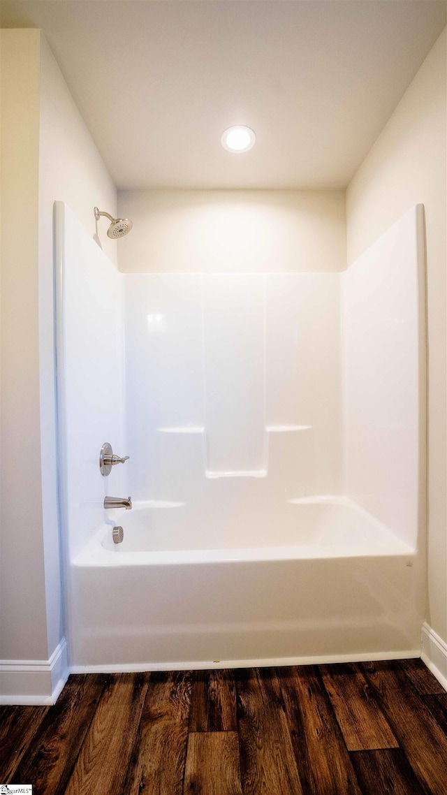 bathroom with washtub / shower combination and wood-type flooring