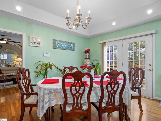 dining space with hardwood / wood-style flooring and ceiling fan with notable chandelier