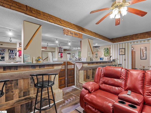 interior space with ceiling fan, bar, and a textured ceiling