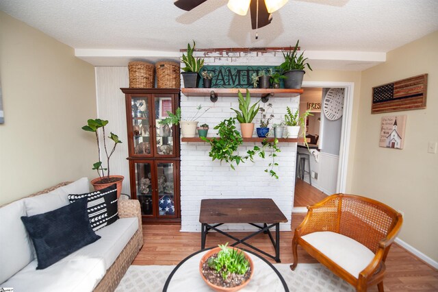 sitting room with ceiling fan, a textured ceiling, and light wood-type flooring