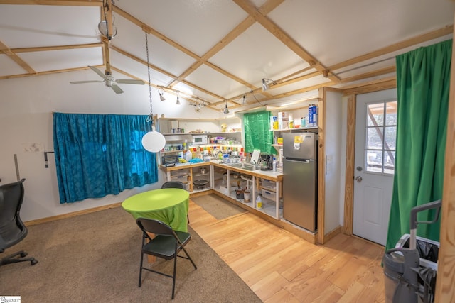 interior space with wood-type flooring, ceiling fan, and stainless steel refrigerator