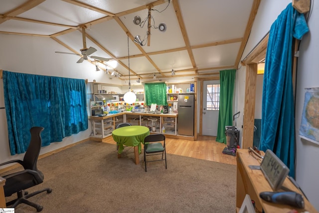 carpeted office space with ceiling fan, a workshop area, and lofted ceiling