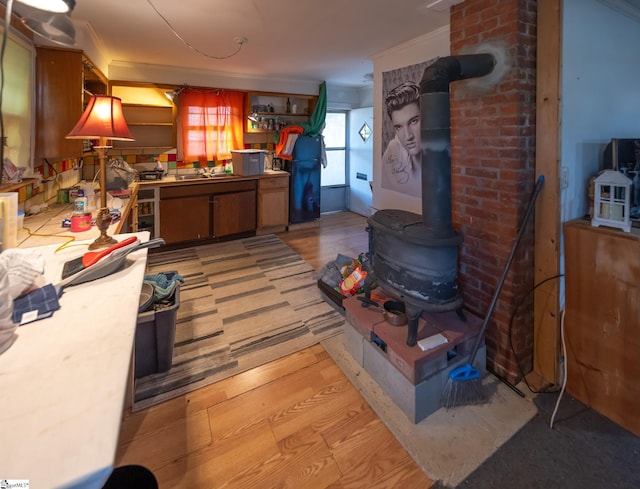 basement featuring sink, light hardwood / wood-style flooring, a wood stove, and ornamental molding