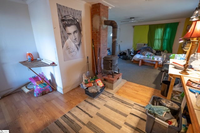 miscellaneous room featuring ceiling fan, hardwood / wood-style flooring, and a wood stove