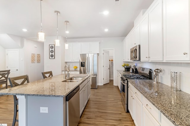 kitchen with stainless steel appliances, an island with sink, pendant lighting, and a kitchen breakfast bar