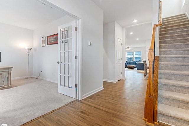 staircase featuring ceiling fan and hardwood / wood-style floors