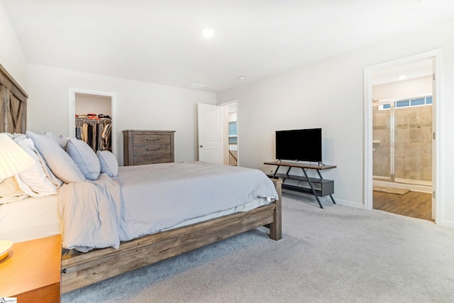 bedroom with a spacious closet, connected bathroom, light colored carpet, and a closet