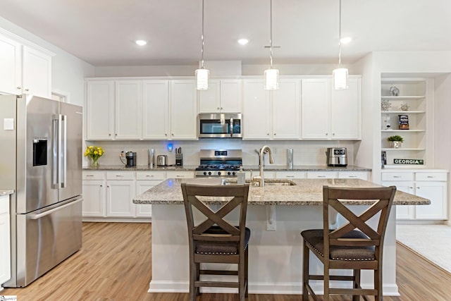 kitchen with sink, a breakfast bar area, decorative light fixtures, an island with sink, and stainless steel appliances