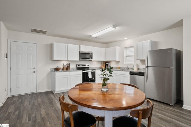 kitchen with stainless steel appliances, dark hardwood / wood-style floors, white cabinets, and light stone counters