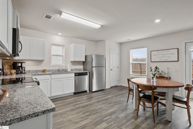 kitchen featuring sink, white cabinetry, appliances with stainless steel finishes, light stone countertops, and hardwood / wood-style floors