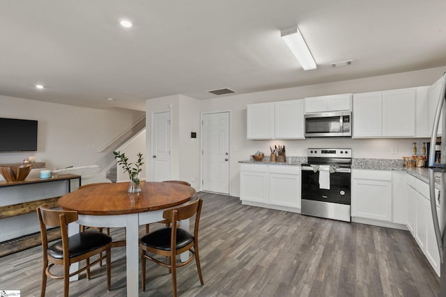 kitchen with appliances with stainless steel finishes, white cabinets, and dark hardwood / wood-style flooring