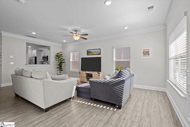 living room with plenty of natural light, ornamental molding, and light wood-type flooring