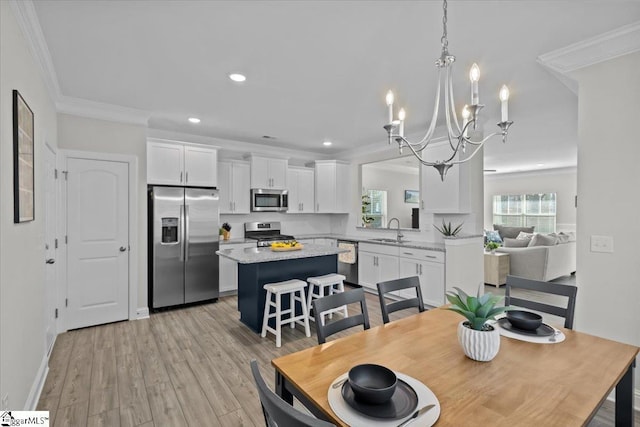 dining space featuring ornamental molding, sink, an inviting chandelier, and light wood-type flooring