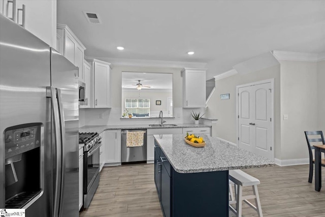 kitchen with white cabinetry, appliances with stainless steel finishes, a center island, and sink