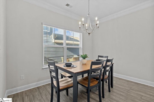 dining area with crown molding, a chandelier, and hardwood / wood-style flooring