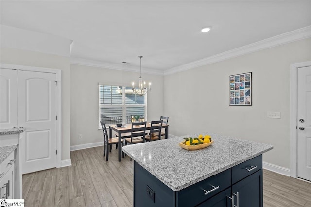 kitchen with crown molding, a chandelier, light wood-type flooring, a kitchen island, and pendant lighting