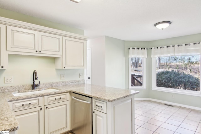 kitchen featuring sink, stainless steel dishwasher, cream cabinetry, and light stone countertops