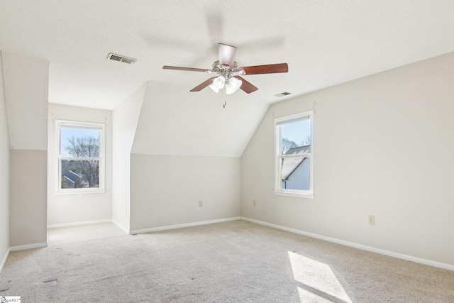 additional living space featuring ceiling fan, light colored carpet, lofted ceiling, and a wealth of natural light