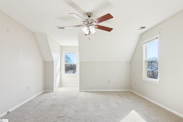 bonus room featuring lofted ceiling, ceiling fan, light carpet, and a healthy amount of sunlight