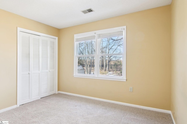 unfurnished bedroom featuring light colored carpet and a closet