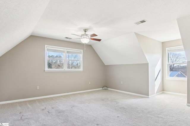 bonus room featuring ceiling fan, lofted ceiling, light colored carpet, and a textured ceiling