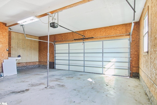 garage featuring a garage door opener and wooden walls