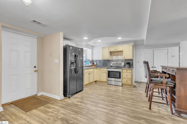 kitchen featuring electric stove, decorative backsplash, light hardwood / wood-style flooring, and black fridge