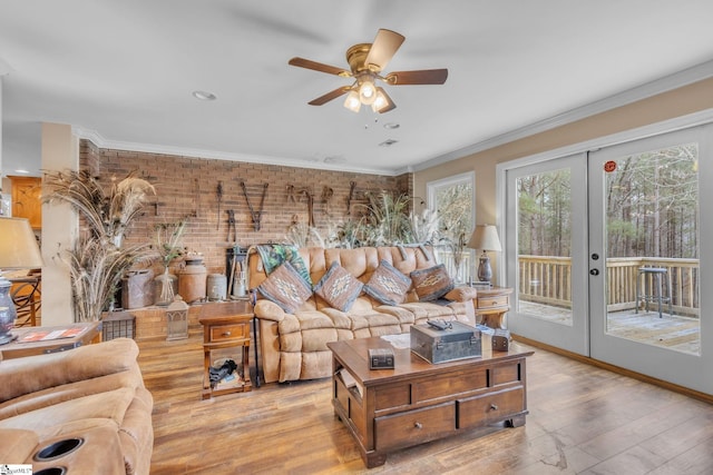 living room with crown molding, light hardwood / wood-style flooring, ceiling fan, brick wall, and french doors