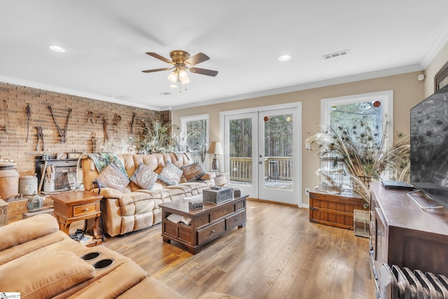 living room featuring crown molding, light hardwood / wood-style floors, french doors, and a wood stove