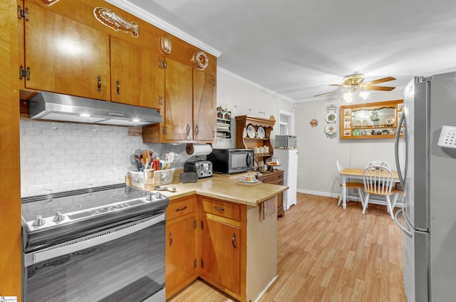 kitchen with appliances with stainless steel finishes, tasteful backsplash, ceiling fan, crown molding, and light hardwood / wood-style flooring