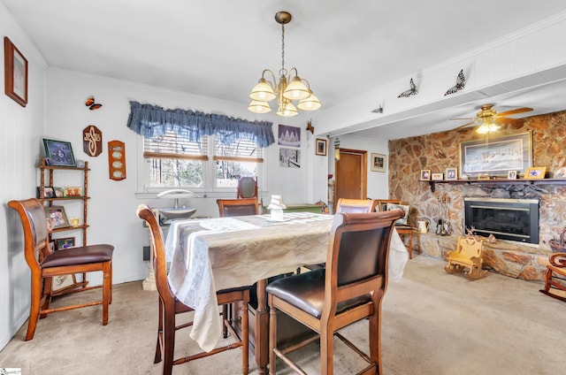 dining space featuring light colored carpet, ornamental molding, and a stone fireplace