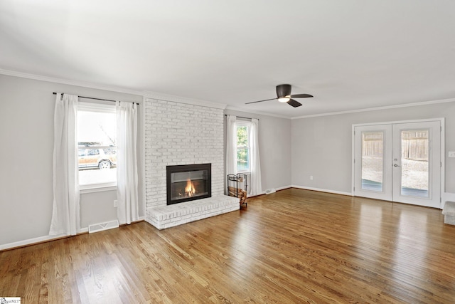 unfurnished living room featuring ornamental molding, a healthy amount of sunlight, hardwood / wood-style floors, and a brick fireplace