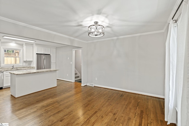 unfurnished living room featuring hardwood / wood-style flooring, crown molding, sink, and a notable chandelier