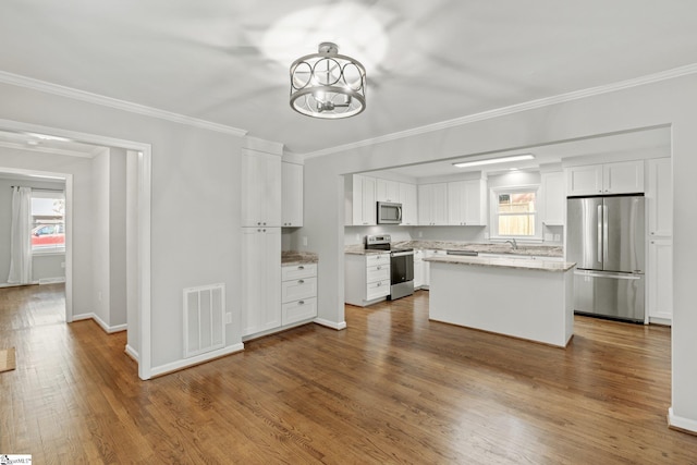 kitchen featuring stainless steel appliances, a center island, and white cabinets