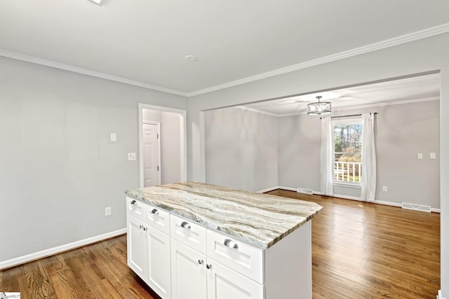 kitchen with white cabinetry, crown molding, light stone counters, light hardwood / wood-style flooring, and a kitchen island