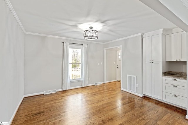 unfurnished bedroom featuring hardwood / wood-style flooring, crown molding, and a notable chandelier