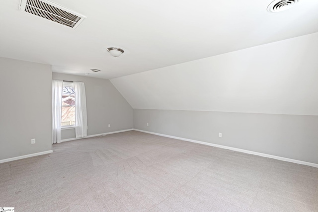 additional living space featuring vaulted ceiling and light carpet