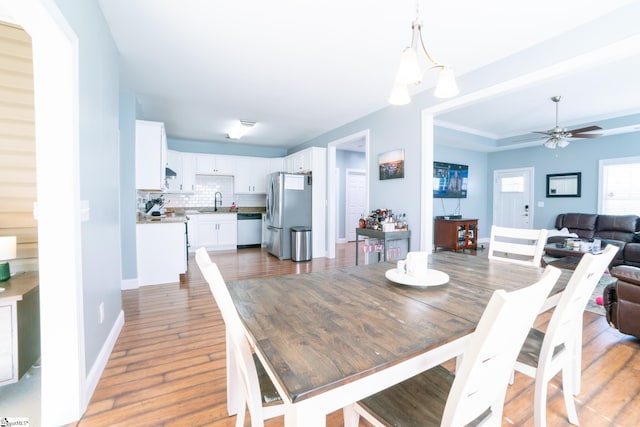 dining space with dark wood-type flooring, ceiling fan, a tray ceiling, and sink