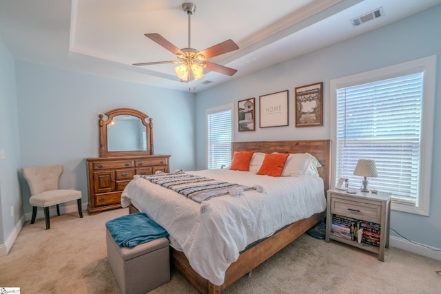 bedroom featuring ceiling fan, a tray ceiling, and light colored carpet