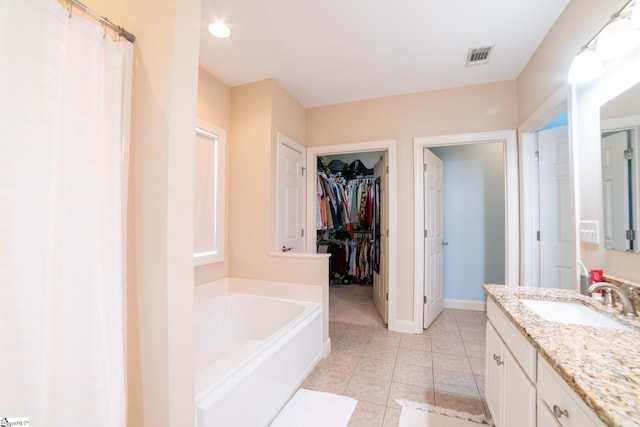 bathroom featuring tile patterned flooring, vanity, and a tub to relax in