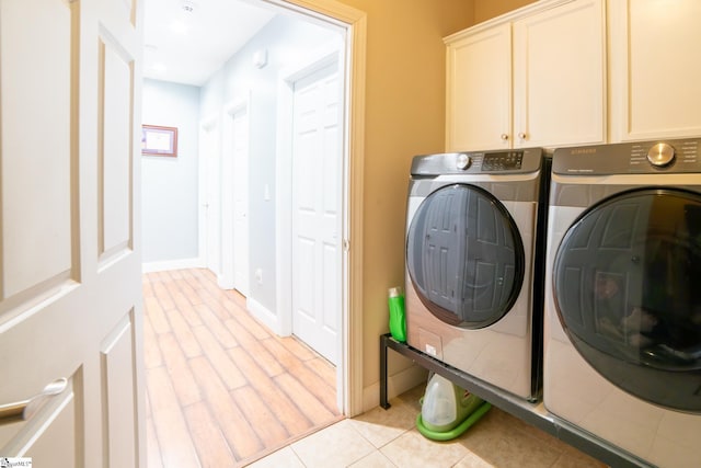 laundry area with light tile patterned flooring, cabinets, and separate washer and dryer