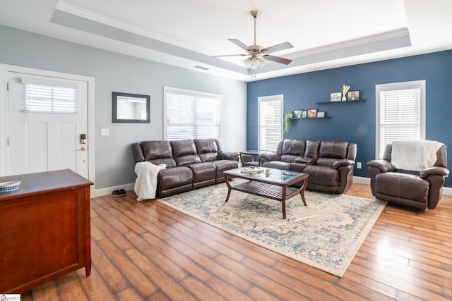 living room with a tray ceiling, ornamental molding, ceiling fan, and hardwood / wood-style flooring